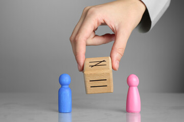 Wall Mural - Gender equality concept. Woman with male and female figures at grey table, closeup