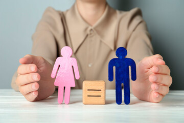 Wall Mural - Gender equality concept. Woman with male and female figures at white table, closeup