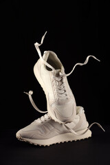 Poster - Pair of stylish sneakers in air against black background