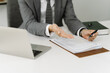 © Nittaya - Business Deal Closing:  A closeup shot of a businessman's hands gesturing towards important legal documents on a desk, signifying a successful business deal or contract signing.