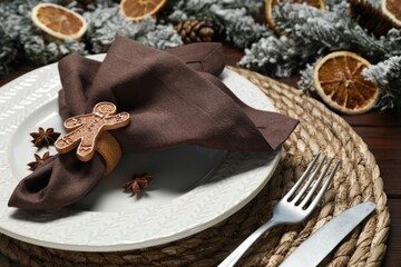 Canvas Print - Christmas place setting with napkin, plate, cutlery and festive decor on wooden table, closeup