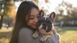 © Itsaya - Asian woman hugging french bulldog in a park, happy vibe, joyful