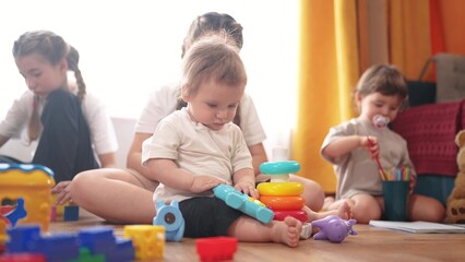 little children play at home lifestyle. happy and full of joy childhood, children's dream concept. a group of children of different ages are playing in the room, various colorful toys lie nearby