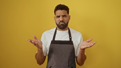 Sticker - Young man in a white shirt and striped apron shrugging over an isolated yellow background, appearing confused and questioning