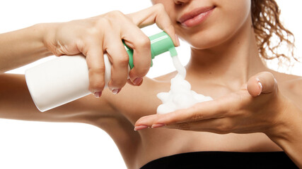 Close-up of hands dispensing skincare foam, focusing on product texture and application against white studio background. Concept of beauty, fashion, appearance, self care. Ad