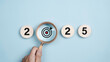 © Deemerwha - Happy new year 2025 with business concept. 2025 year number with Target icon inside the golden magnifying glass on light blue background. Planning for goal and success concepts. New Year resolution