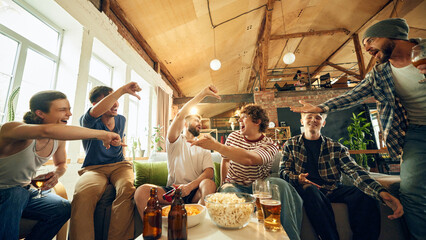 Crucial moment on screen leaves everyone at edge of their seats. Some players pumped, while others facepalm in defeat. Concept of football fans, sport evens, video games and cybersport.