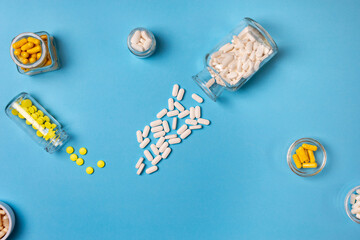 Dietary supplements, vitamins and minerals tablets from above on a blue background.