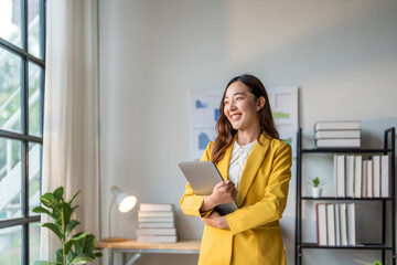 Wall Mural - young businesswoman holding laptop smiling and looking out the window in office