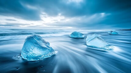 Wall Mural - Three large icebergs rest on a black sand beach with crashing waves, under a dramatic sky.