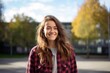 © Markus Schröder - Portrait of a happy woman in her 30s wearing a comfy flannel shirt in front of modern university campus background