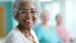 © JAYDA RIN - Senior Black woman smiling warmly as she participates in a group activity with other residents in a bright nursing home   group activity, happy senior