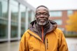© Markus Schröder - Portrait of a glad afro-american man in his 60s wearing a windproof softshell over modern university campus background
