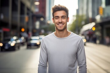 Poster - Portrait of a grinning man in his 20s showing off a lightweight base layer while standing against bustling city street background