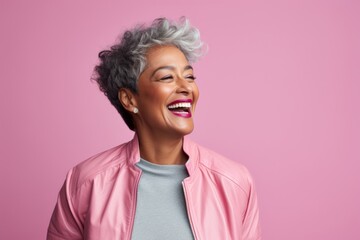 Poster - Portrait of a joyful indian woman in her 60s wearing a trendy bomber jacket while standing against pastel or soft colors background