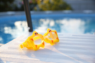 Canvas Print - Yellow swimming goggles for kids on ladder outdoors, closeup. Space for text