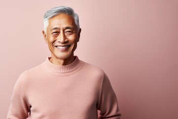 Canvas Print - Portrait of a smiling asian man in his 60s dressed in a warm wool sweater isolated on pastel or soft colors background