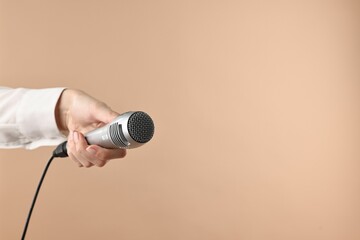 Wall Mural - Woman with microphone on beige background, closeup. Space for text