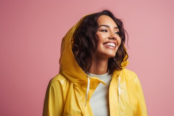 Canvas Print - Portrait of a smiling indian woman in her 20s wearing a vibrant raincoat in front of pastel or soft colors background