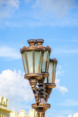 Street lamp with three lamps against blue sky.