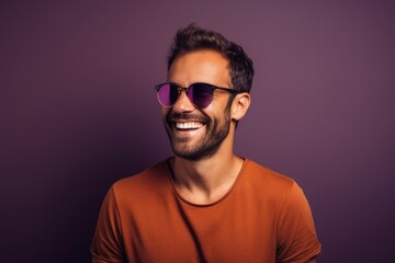 Wall Mural - Portrait of a smiling man in his 30s wearing a trendy sunglasses in front of solid color backdrop