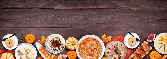 Poster - Autumn desserts bottom border. Table scene with assorted gourmet fall sweet foods. Top down view over a dark wood banner background. Copy space.