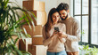 © Dina Photo Stories - happy mixed race couple standing in new apartment against moving boxes, using smart phone. moving, real estate, new, home, relocation, transportation service, movers, delivery, rental