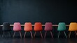 ©  Shomixer - A row of vibrantly colored chairs set against a plain, dark background, showcasing a contrast between lively furniture design and a minimalistic, stark environment.