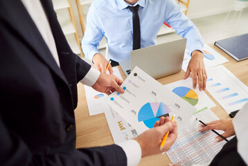 Businessman standing in the office holding a paper with a diagram. A group of business people in the office check reports, hands and documents close-up. Concept audit of the company, inspection