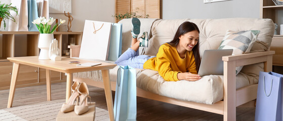 Poster - Young Asian woman with laptop shopping online at home