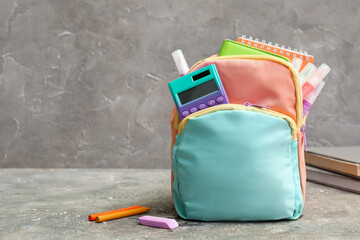 Wall Mural - Colorful school backpack with notebooks, calculator and markers on grey grunge table near wall