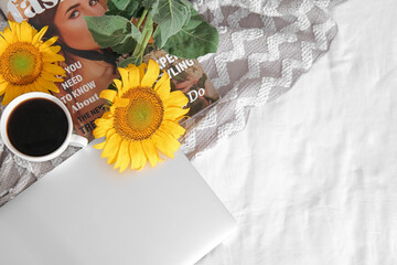 Sticker - Beautiful sunflowers, cup of coffee, magazine and modern laptop on fabric background