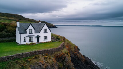 Aufkleber - A white house sits on a hill overlooking the ocean. The sky is cloudy and the water is calm. The house is surrounded by a stone wall and there are several potted plants in the yard