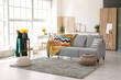 © Pixel-Shot - Interior of stylish room with cozy sofa and bouquet of daffodil flowers in vase