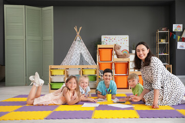 Poster - Nursery teacher with little children drawing on floor in kindergarten