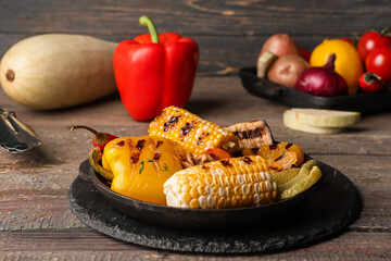 Frying pan with grilled vegetables on wooden table, closeup