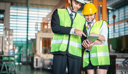 helmet, safety, manufacturing, industrial, blueprint, colleague, cooperation, discussion, foreman, hard hat. Two people in safety gear are looking at a tablet. One of them is pointing on the screen.