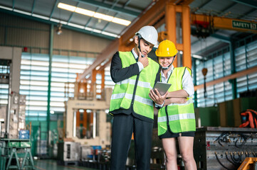 engineer, helmet, architect, safety, manufacturing, machinery, industrial, colleague, discussion, expertise. Two people in safety gear looking at a tablet. Scene is serious and focused.