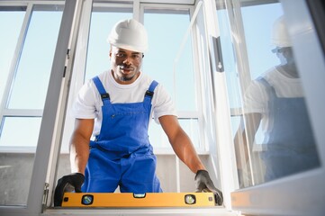 Wall Mural - Workman in overalls installing or adjusting plastic windows in the living room at home