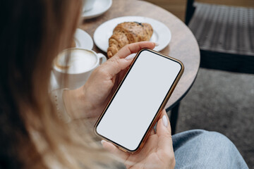 Mockup woman's hand holding using smart phone with white blank screen at coffee shop, mobile app design and advertising, online marketing