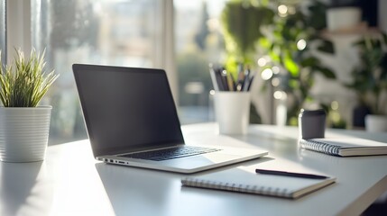 Poster - A white desk with only a laptop and a notebook in a bright indoor office, creating a minimal yet functional workspace, photographed in portrait.