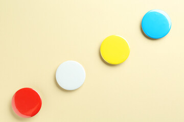 Wall Mural - Colorful button badges on beige background, flat lay. Mockup for design