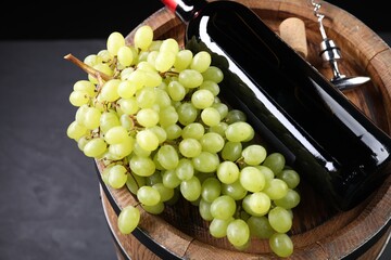 Canvas Print - Corkscrew with metal handle, bottle of wine, grapes, cork and wooden barrel on grey table, closeup