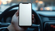 © 沈军 贡 - Close-up of a hand holding a smartphone with a blank white screen mockup in a car interior,