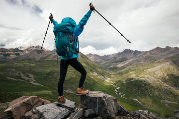 Wall Mural - Cheering hiking woman on high altitude mountain top