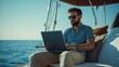 © Jiraphat - A man working remotely on a laptop aboard a yacht, enjoying the sunlit sea view, blending leisure with productivity.