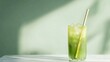 © Wish Craft Arts - A refreshing green drink with ice and a straw in a tall glass on a white marble surface against a green background.