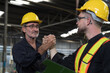 © amorn - Two male engineer join hands together in industry factory. Finished, completed work concept