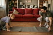 © La Famiglia - Caucasian little girl and her father enjoy free time at home in the living room, preparing for a home workout together