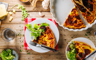 Top view of a plate with a slice of quiche and fresh salad, perfect for a balanced meal. ..